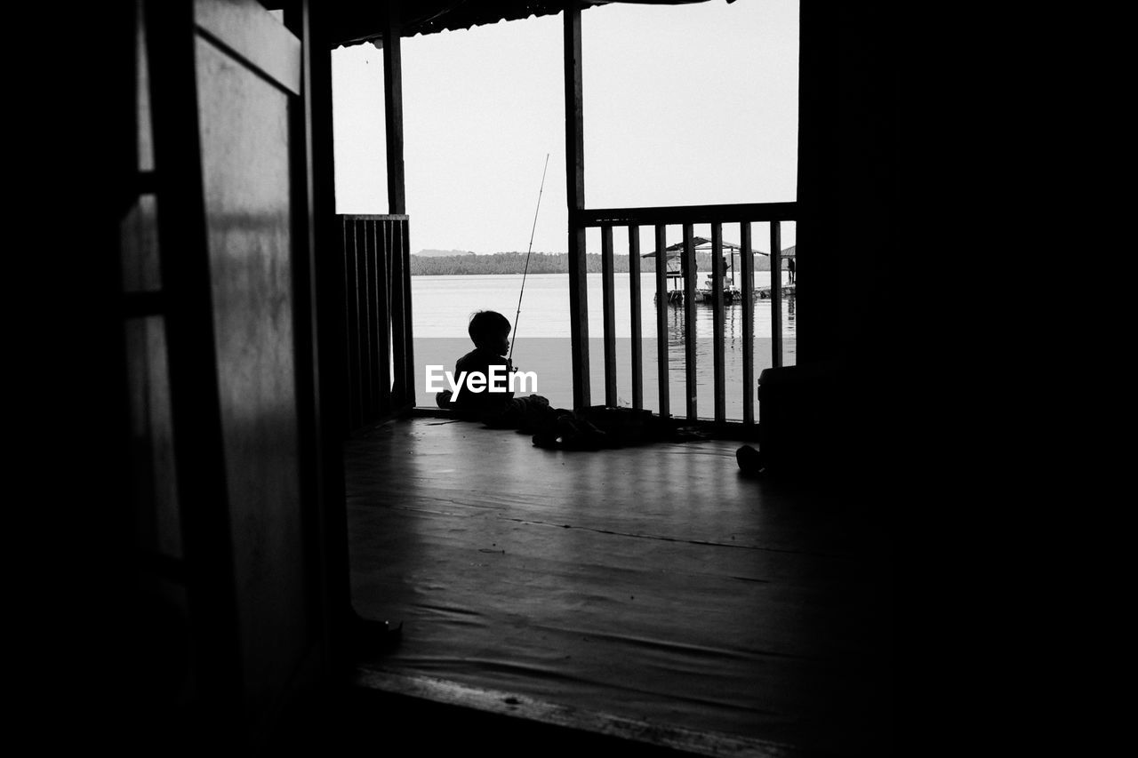 SIDE VIEW OF SILHOUETTE MAN SITTING BY WINDOW