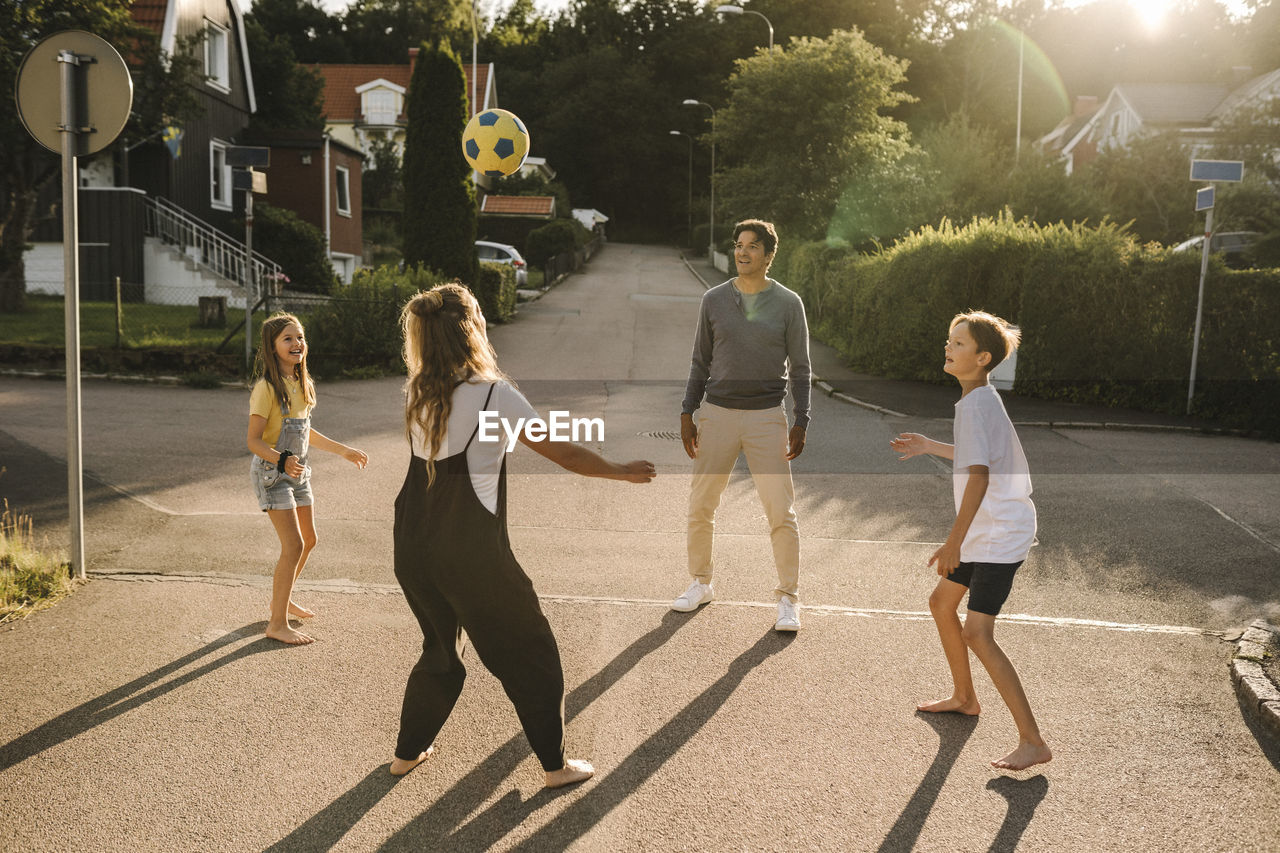 Happy family playing with soccer ball on road