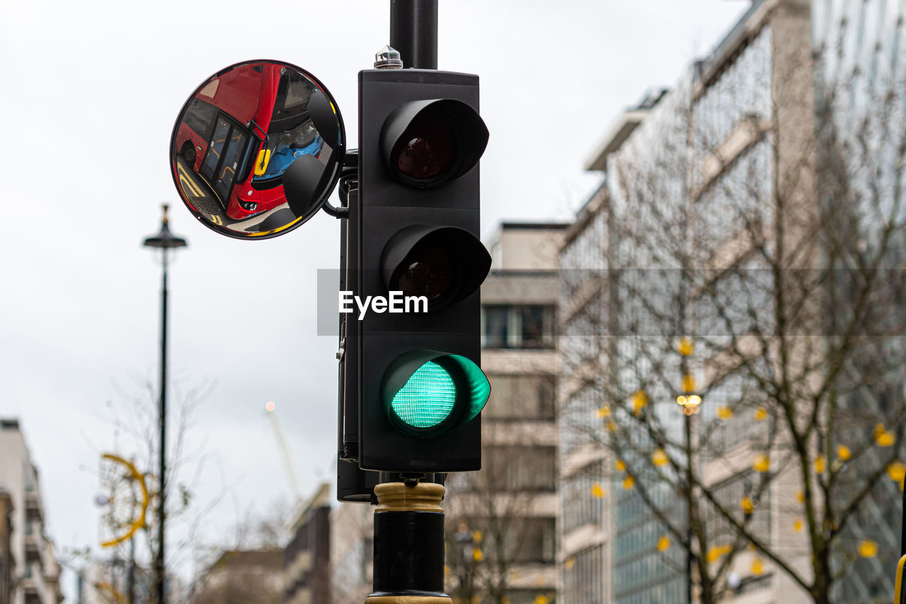 Green traffic light signal and traffic convex mirror with the reflection of the red bus