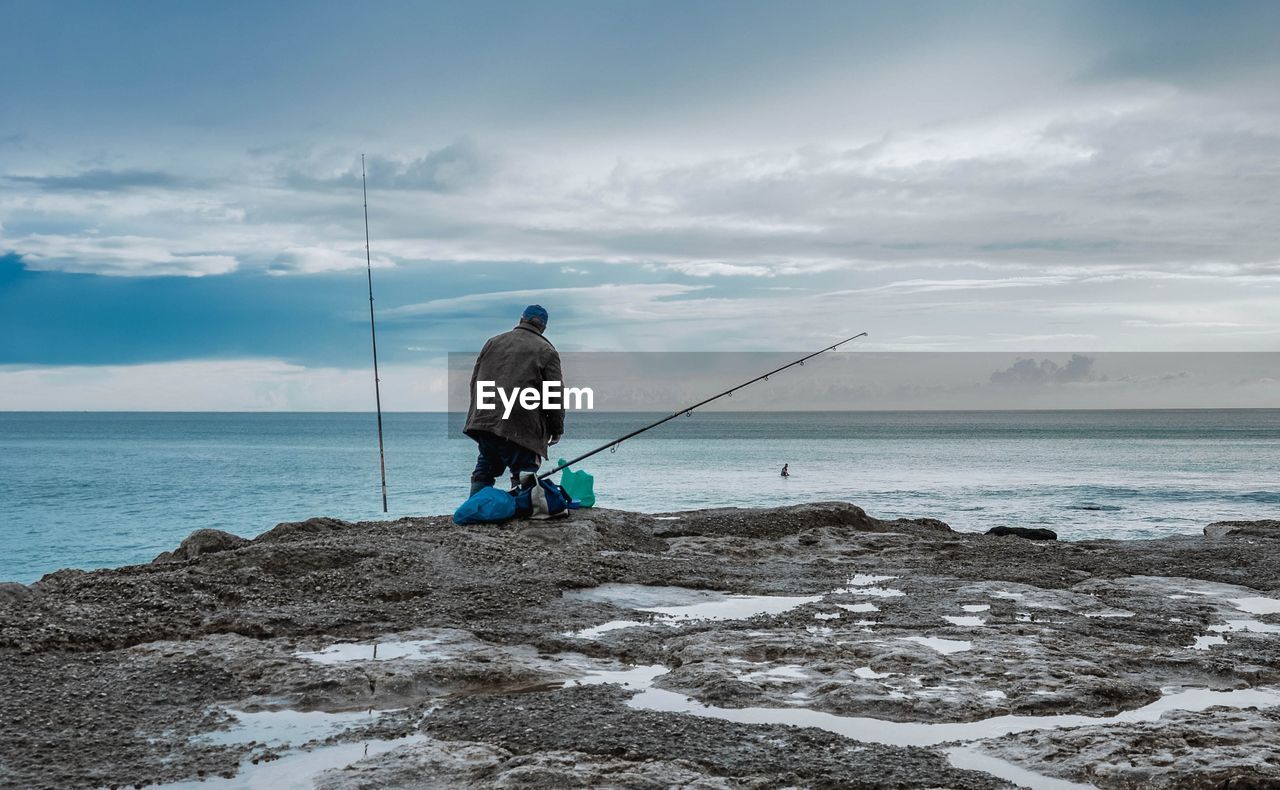 Man with fishing rod at coastline
