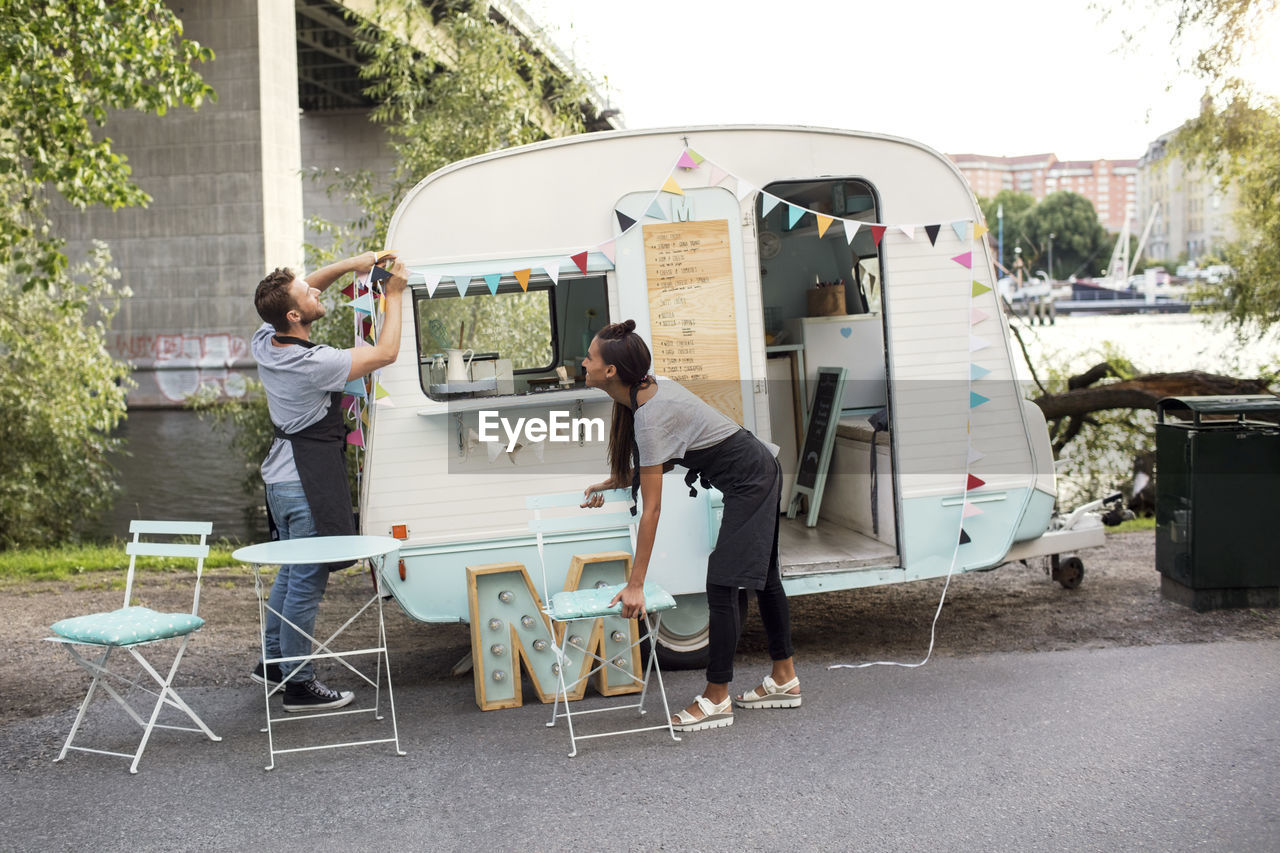 Male and female owners working outside food truck on street