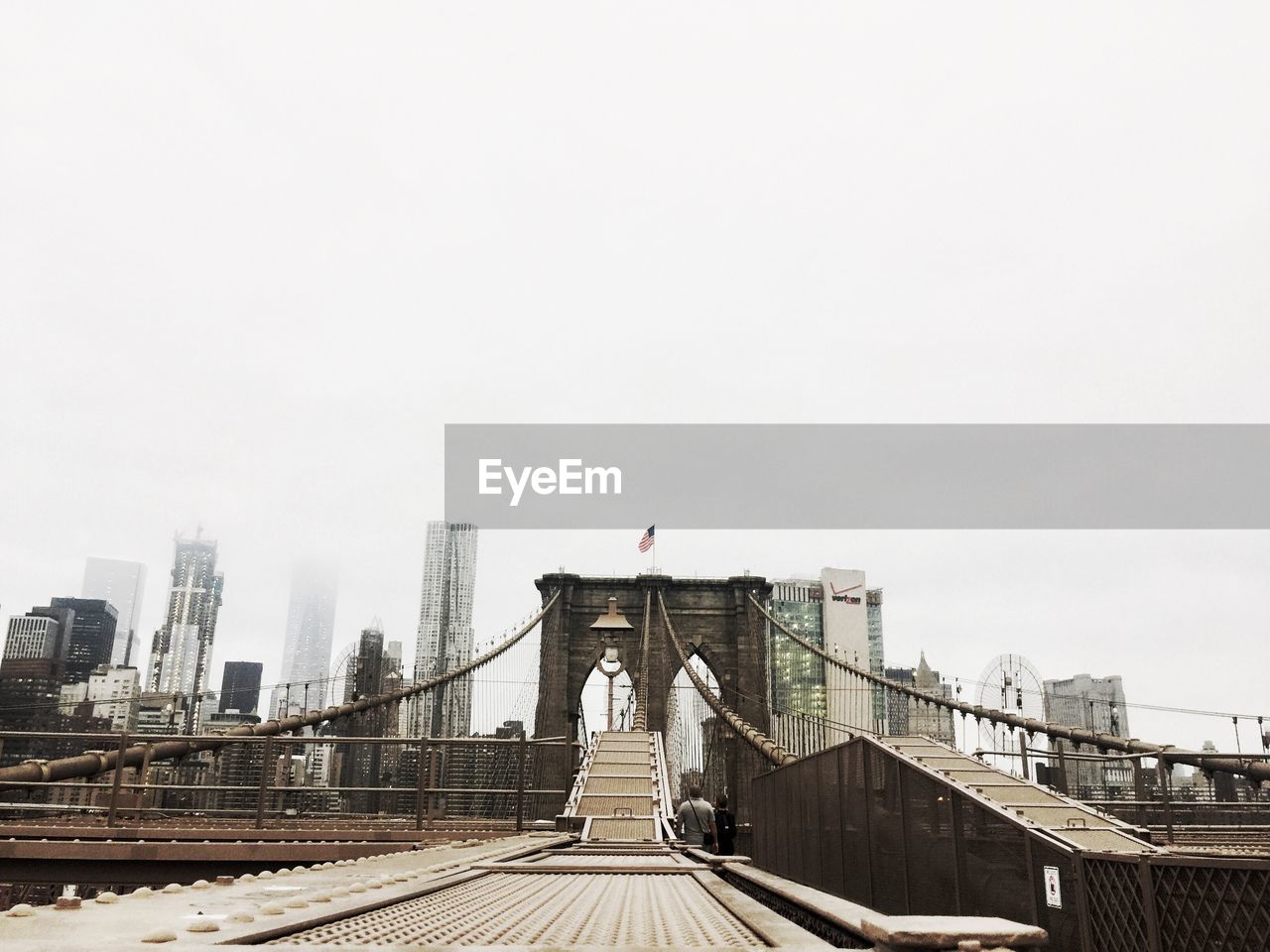 Suspension bridge in city against clear sky