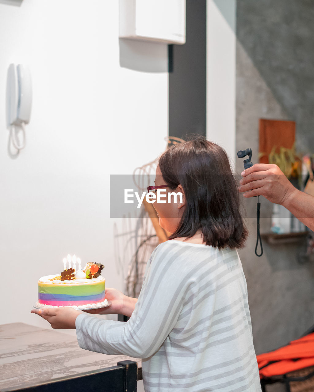 Girl holding cake while standing against wall