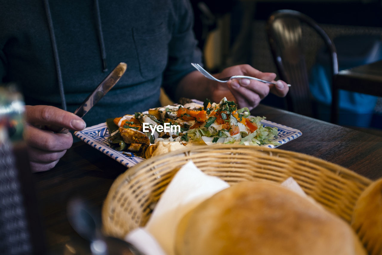 Midsection of man heaving meal at table