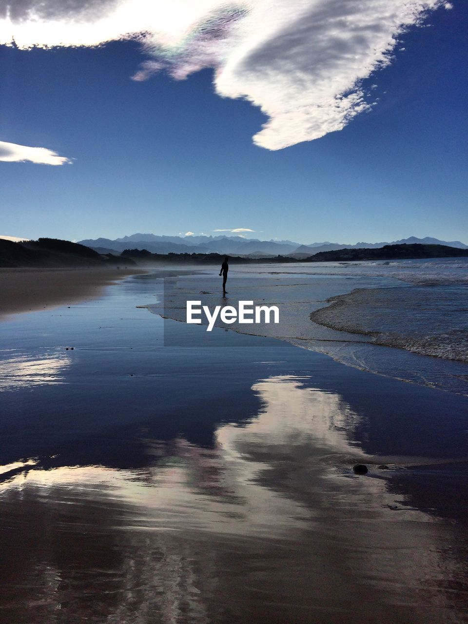 Silhouette man standing on calm beach