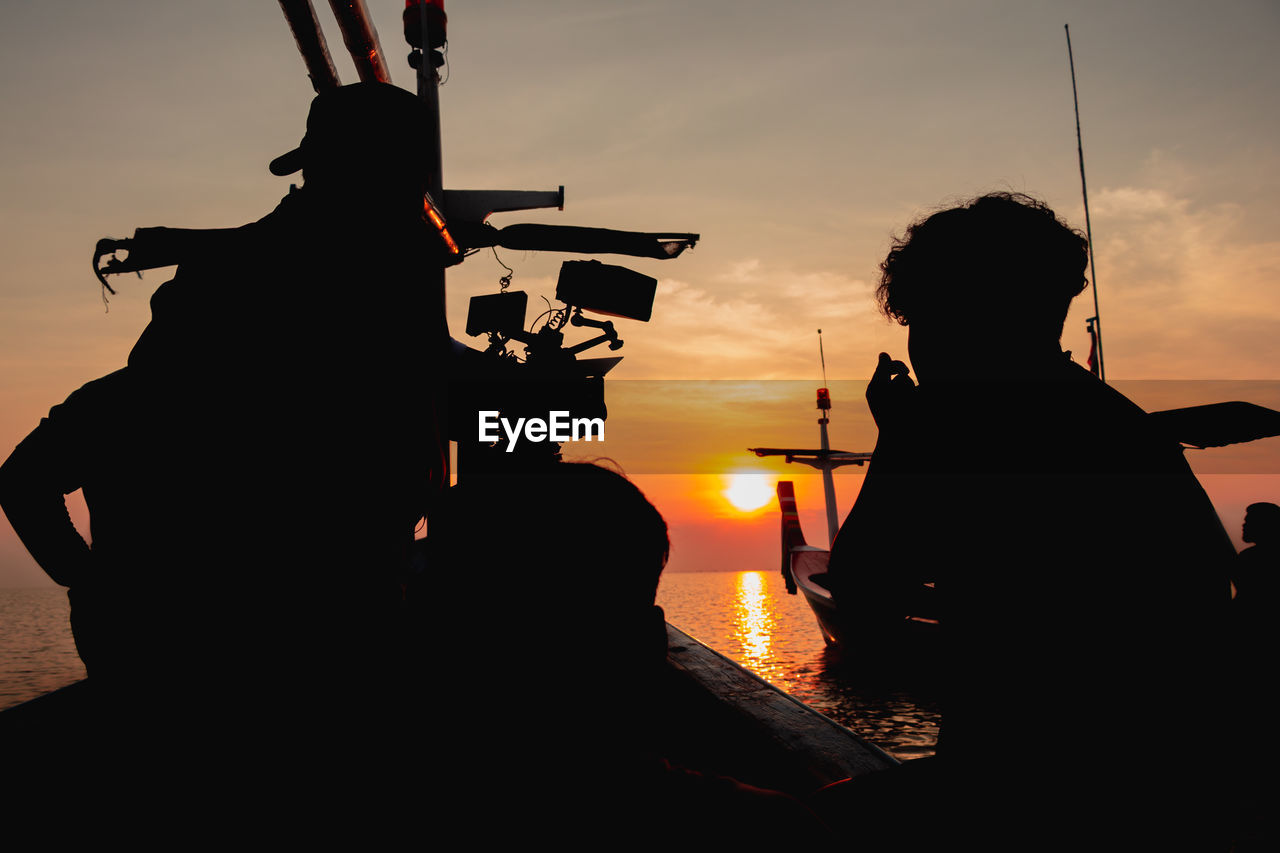 SILHOUETTE PEOPLE SITTING AGAINST ORANGE SKY