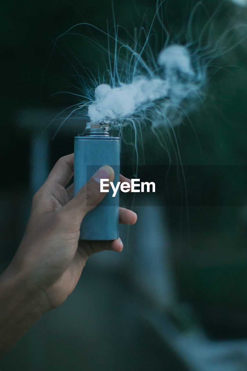 Close-up of man holding cigarette against blurred background