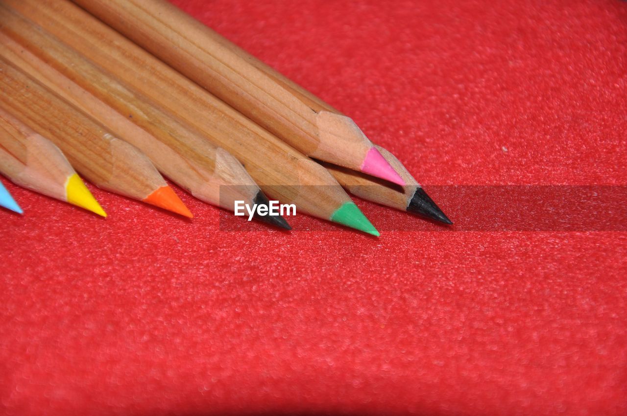 pencil, red, writing instrument, colored pencil, no people, close-up, multi colored, still life, indoors, craft, wood, sharp, education, creativity, large group of objects, high angle view, in a row, paper, variation, writing, table