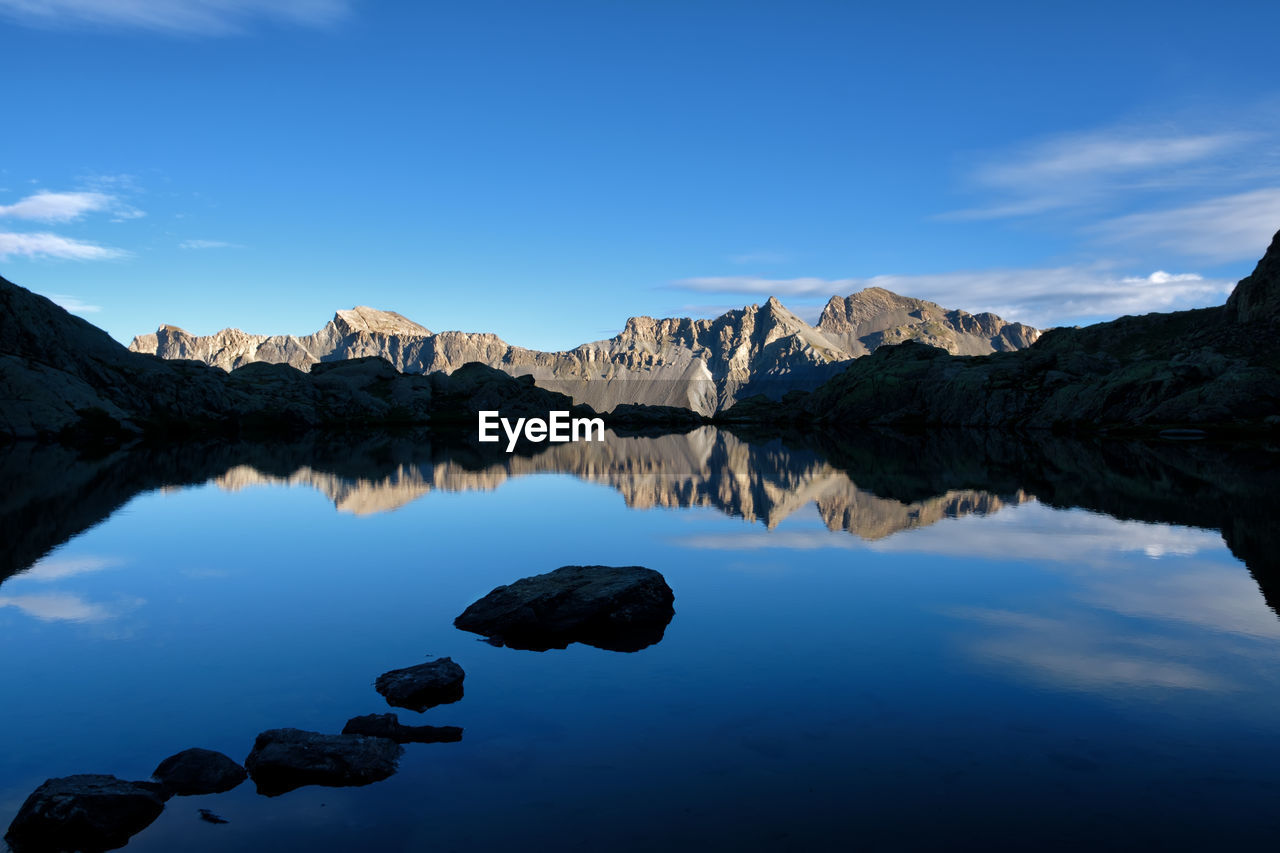 Scenic view of lake and mountains against blue sky