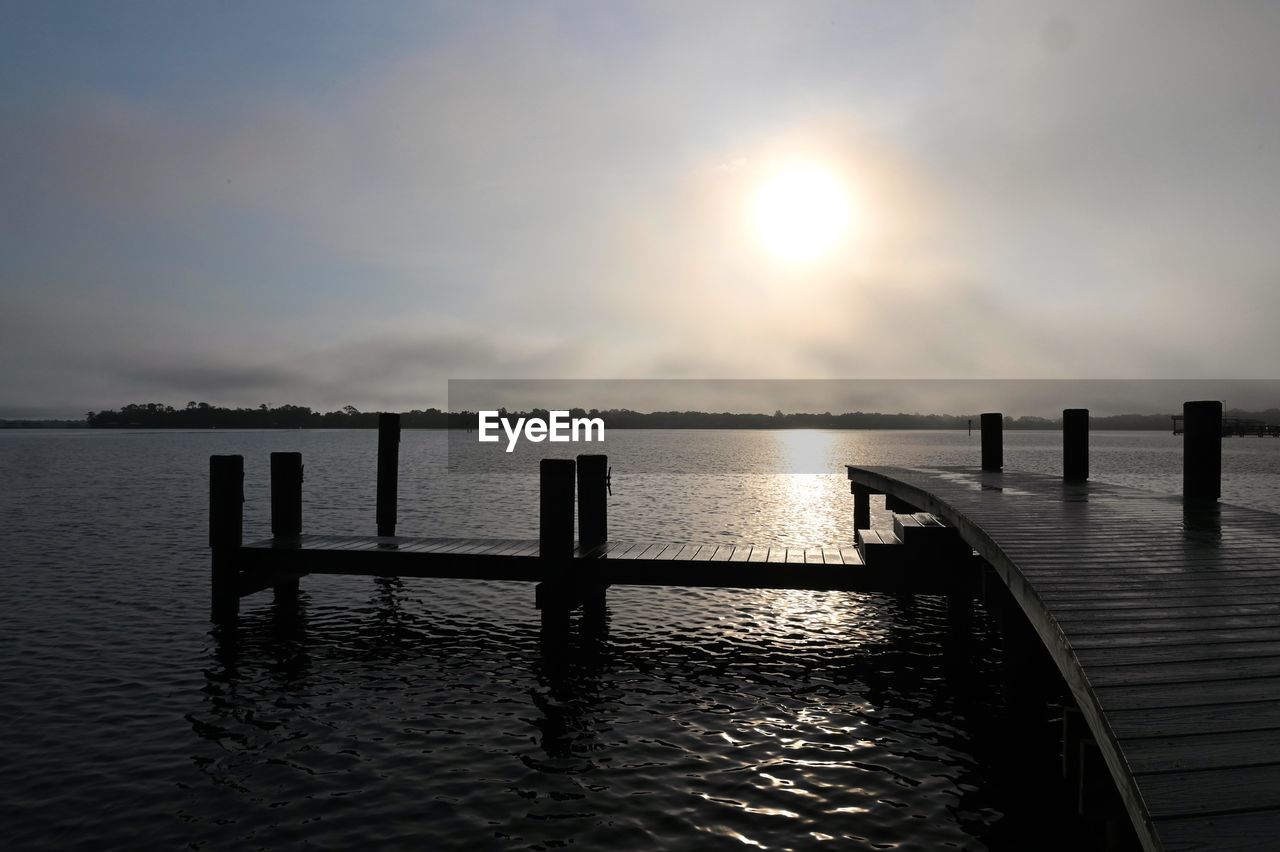 WOODEN POSTS IN SEA AGAINST SKY