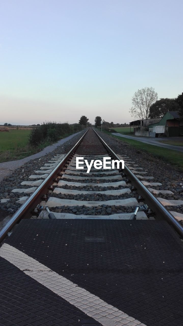 RAILROAD TRACK ON COUNTRYSIDE LANDSCAPE AT SUNSET