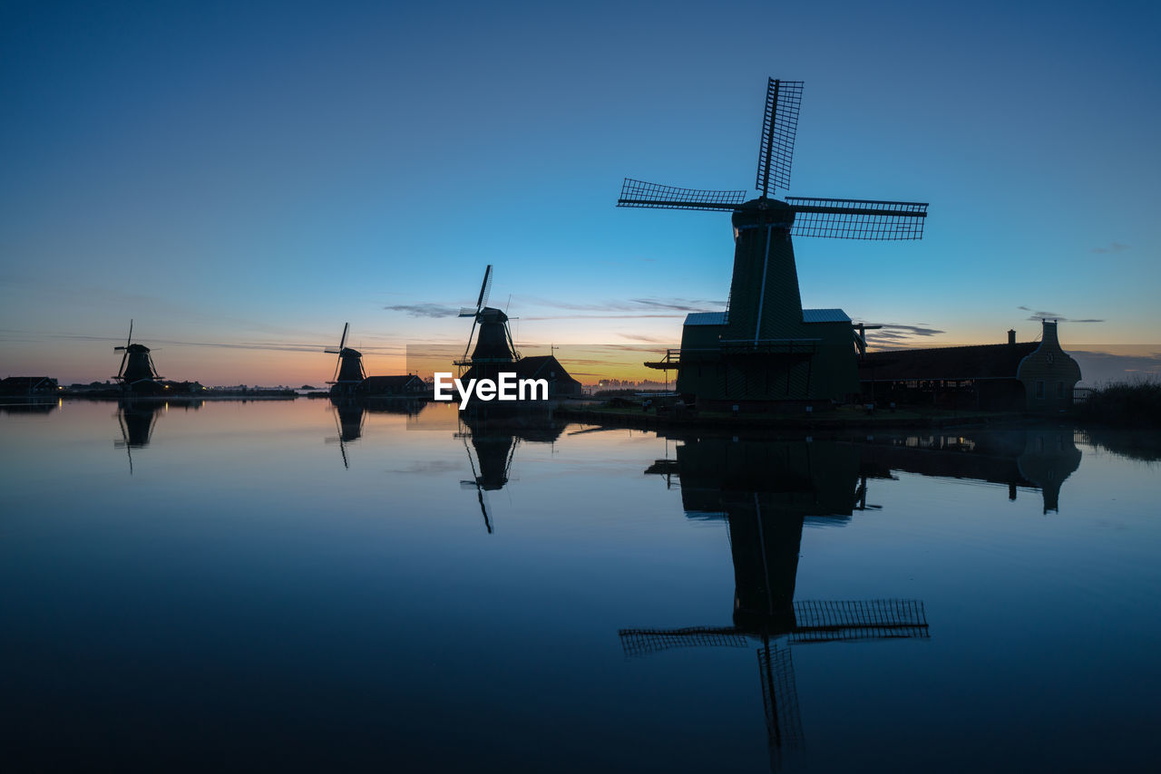 Silhouette cranes against sky during sunset