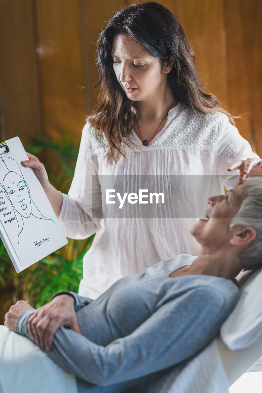 Masseur showing book to woman at spa