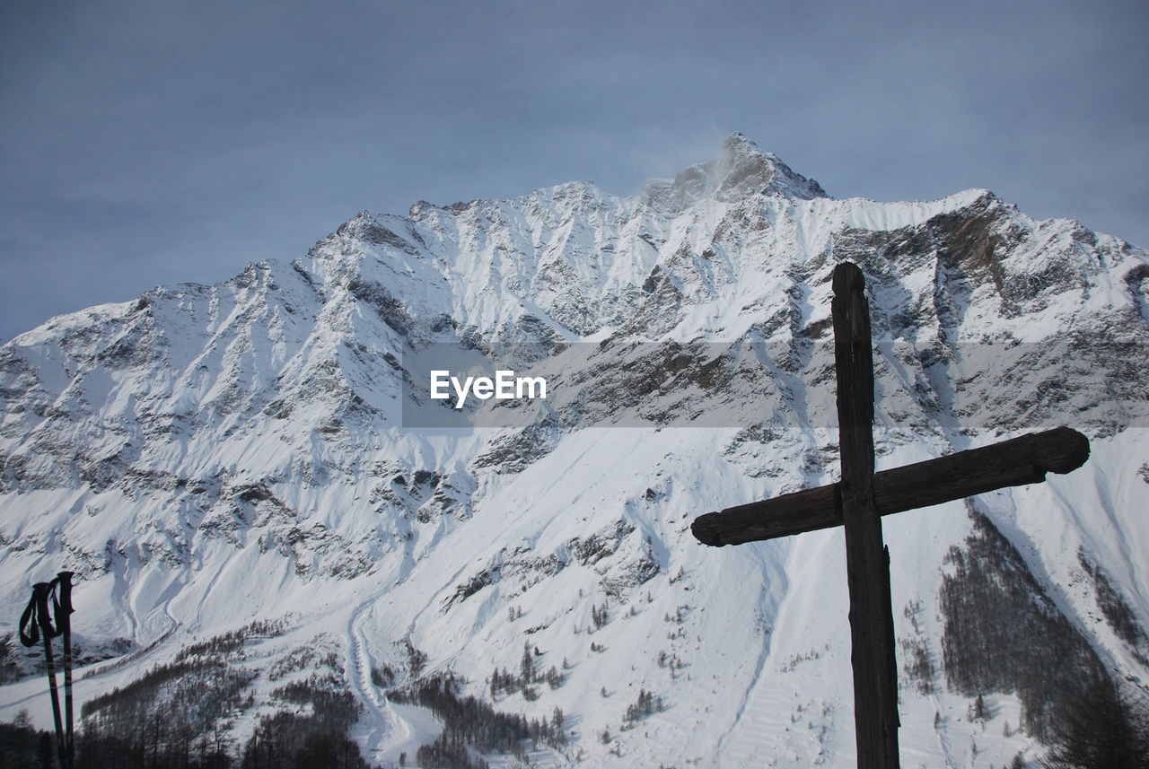 Cross on snowcapped mountain against sky