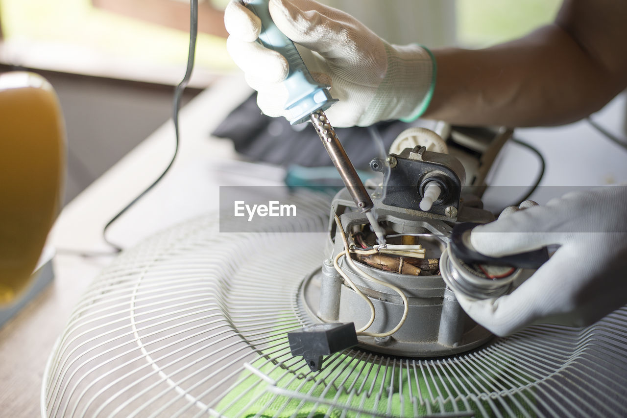 Close-up of hand repairing electric fan