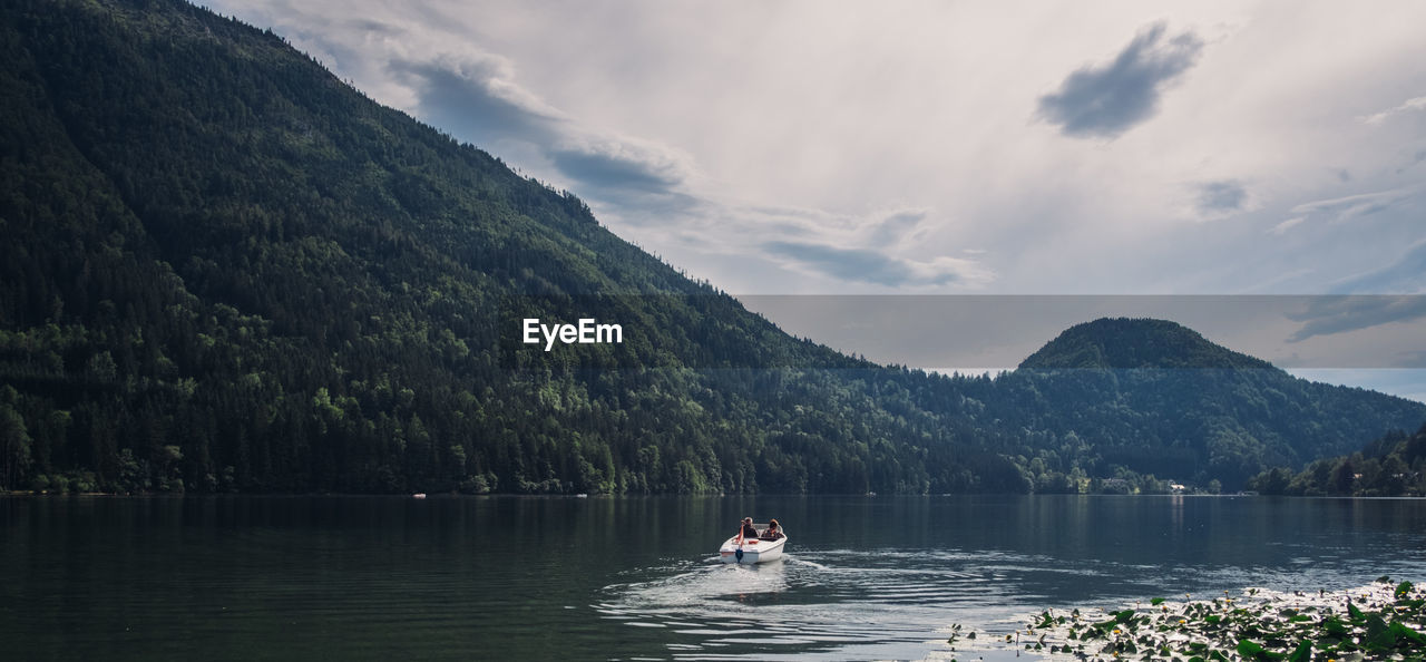 People in boat on lake against sky