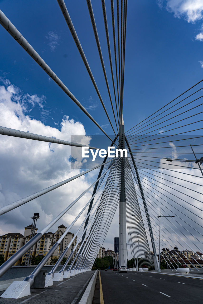 transportation, sky, architecture, bridge, built structure, cloud, cable-stayed bridge, city, cable, road, nature, suspension bridge, no people, building exterior, street, the way forward, mode of transportation, travel destinations, blue, line, travel, steel cable, day, skyscraper, outdoors, cityscape, motor vehicle, car, mast, landmark, vanishing point, city life, traffic, building, diminishing perspective