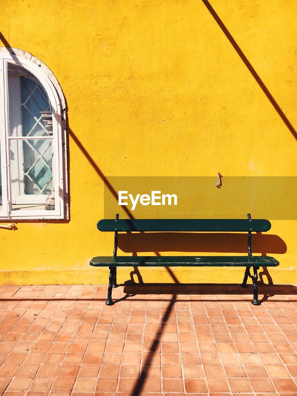 Bench against yellow building during sunny day