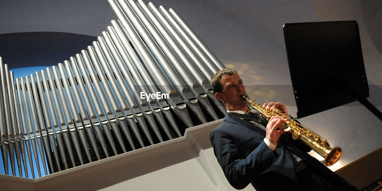 LOW ANGLE VIEW OF MAN PLAYING MUSIC IN OFFICE