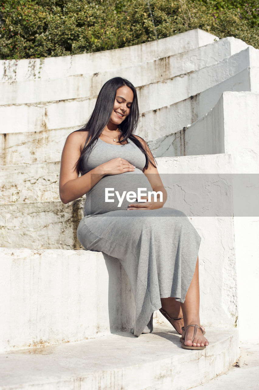 Young pregnant brazilian woman touching her belly in a garden person