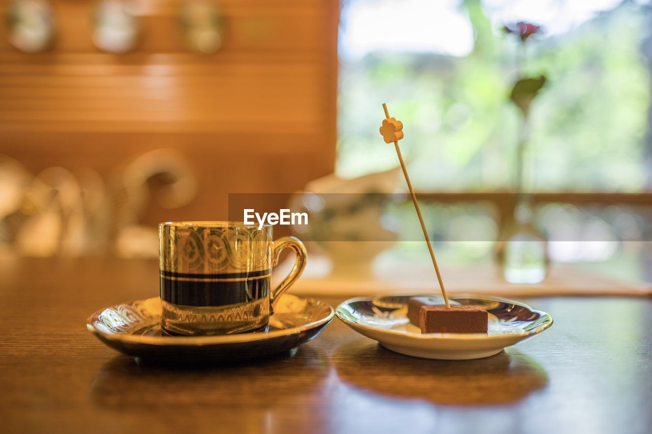 CLOSE-UP OF COFFEE CUP ON TABLE AGAINST WALL