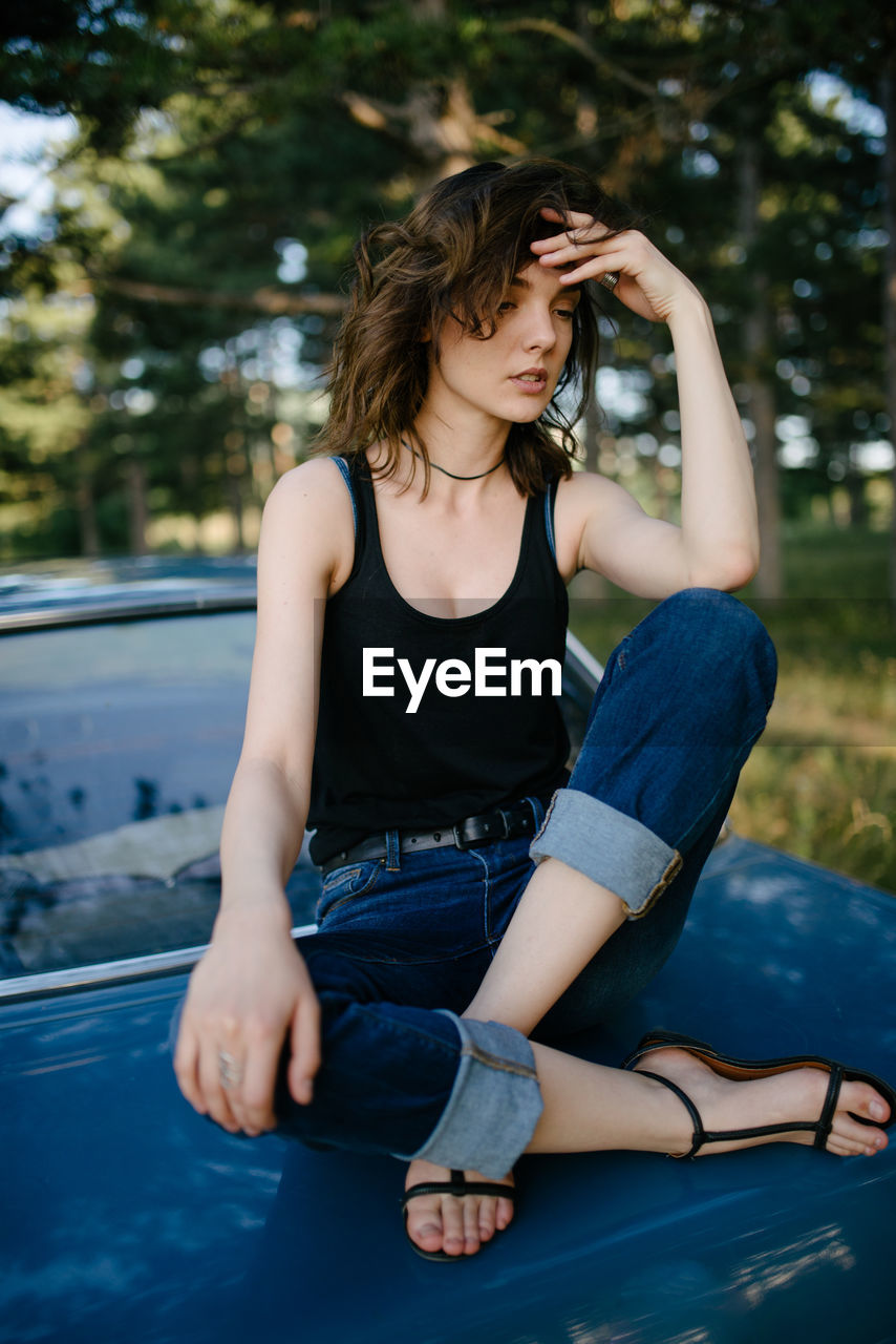 Young hipster woman sitting and possing on a blue vintage car.