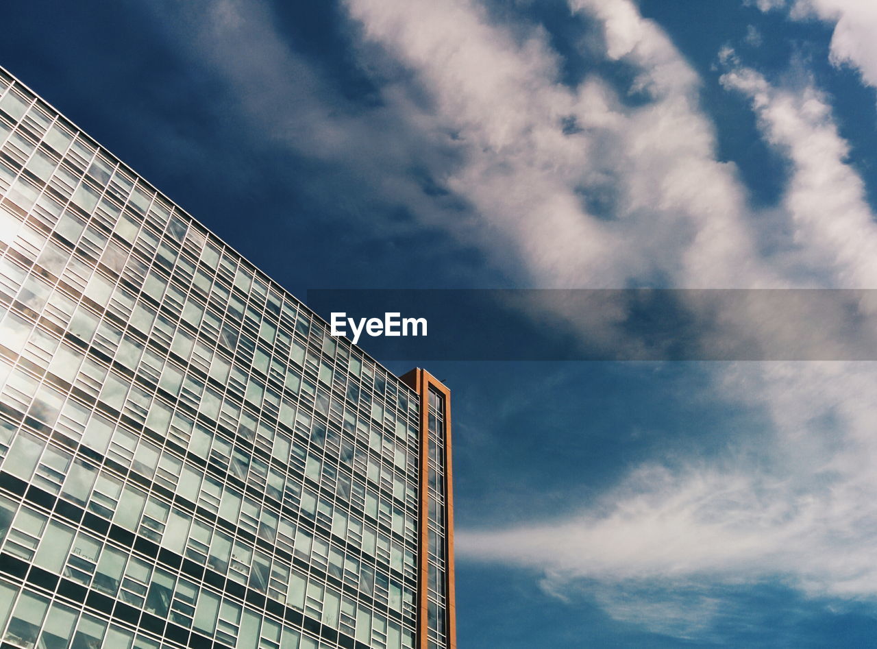 Low angle view of modern building against cloudy sky