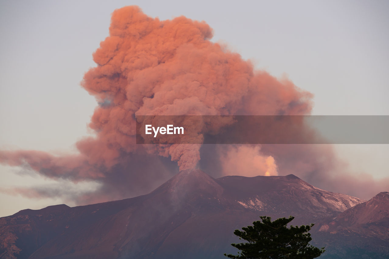 Low angle view of the cityscape against the sky during the strombolian eruption of etna