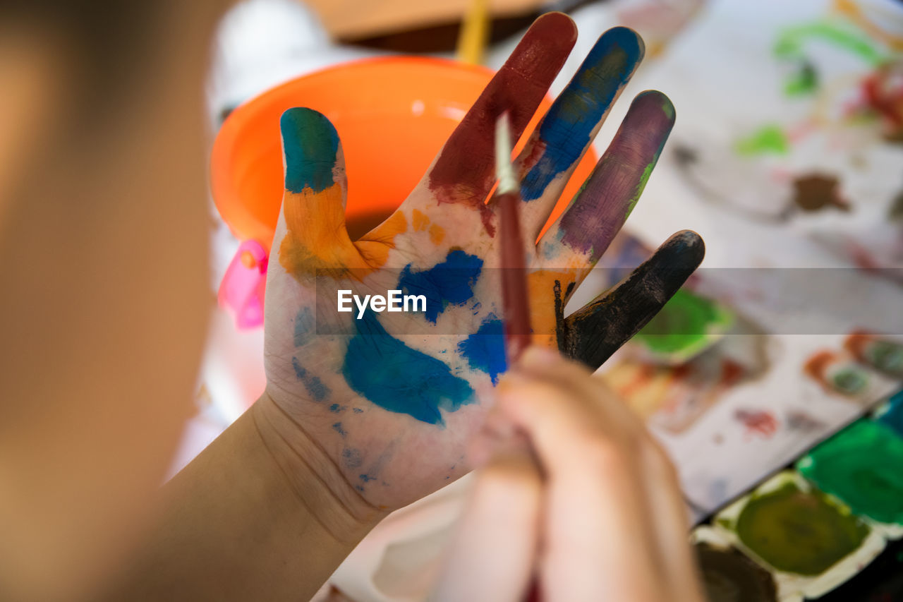 Cropped hands of child with watercolor paints