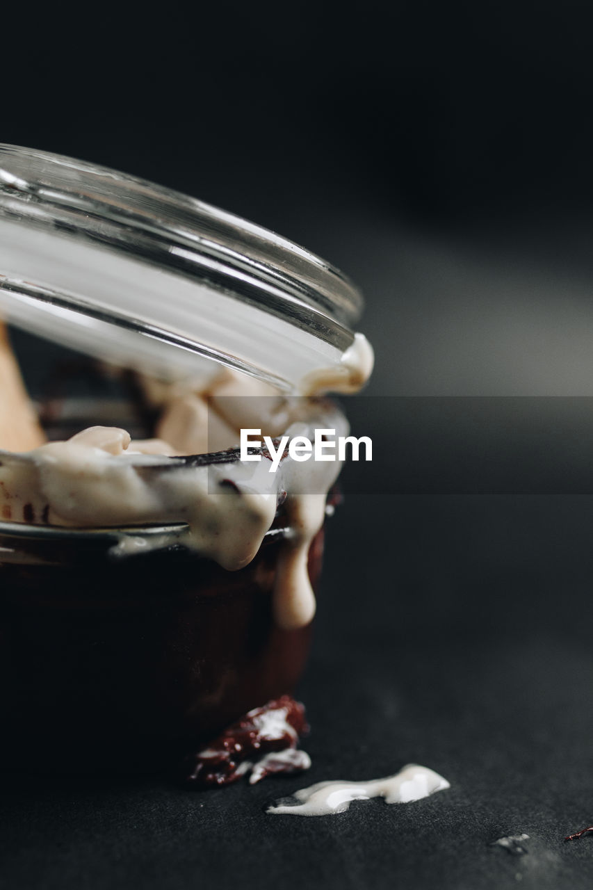 Close-up of sweet food in jar against black background