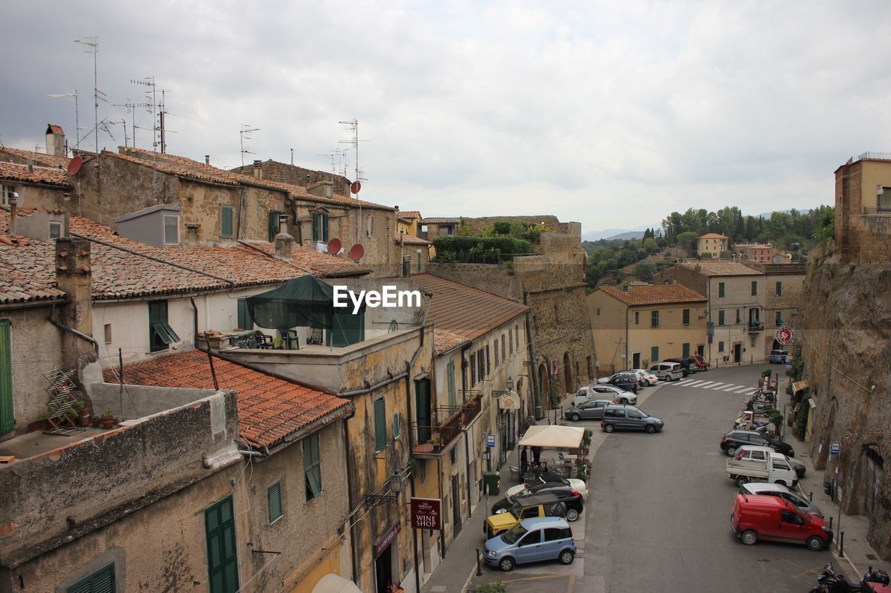 Vehicles on road amidst buildings in city against sky