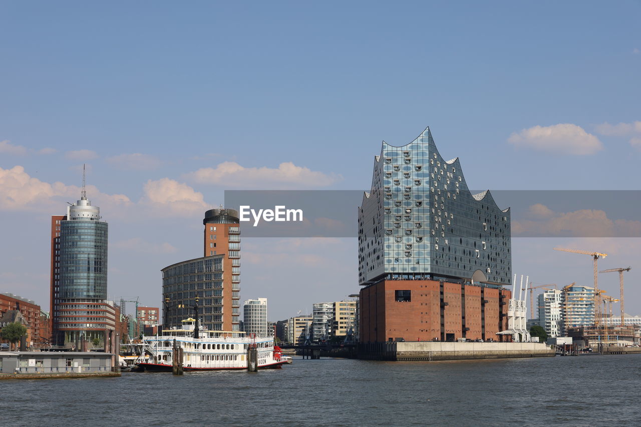 Sea by modern buildings against sky in hamburg 