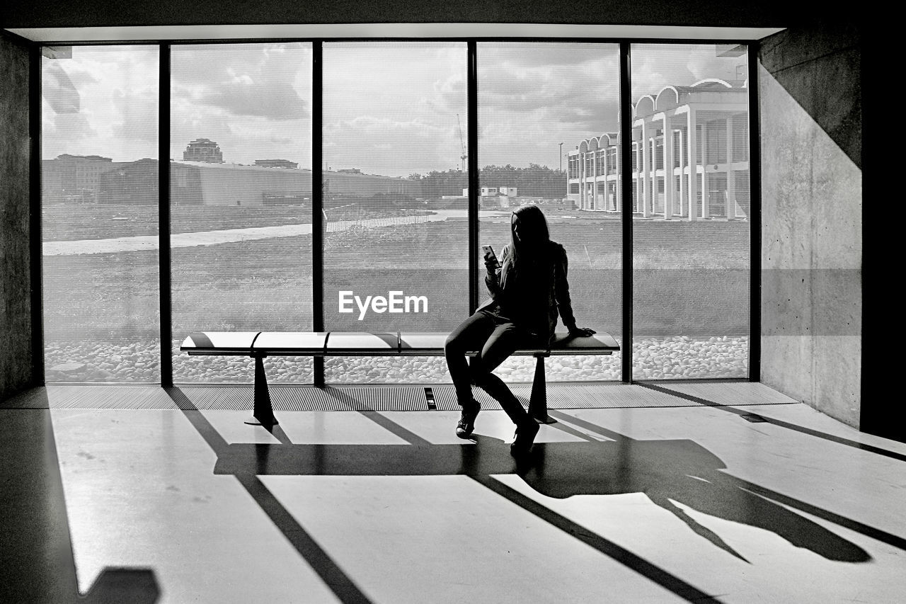 FULL LENGTH OF WOMAN SITTING AT WINDOW