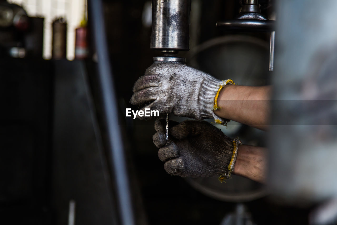 Cropped hands of worker holding work tool at workshop