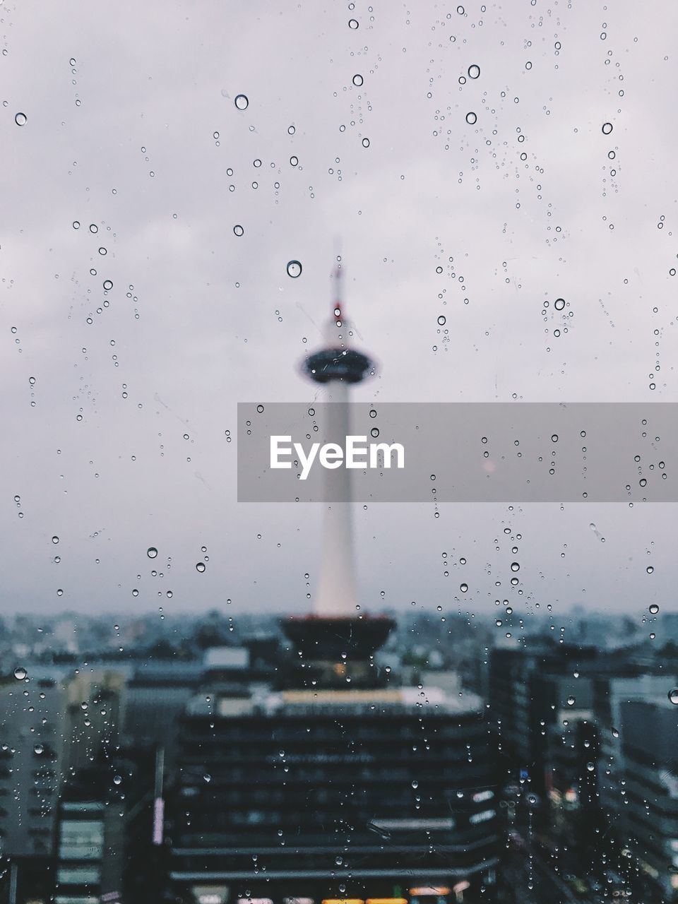 CLOSE-UP OF WATER DROPS ON FOUNTAIN AGAINST BUILDINGS