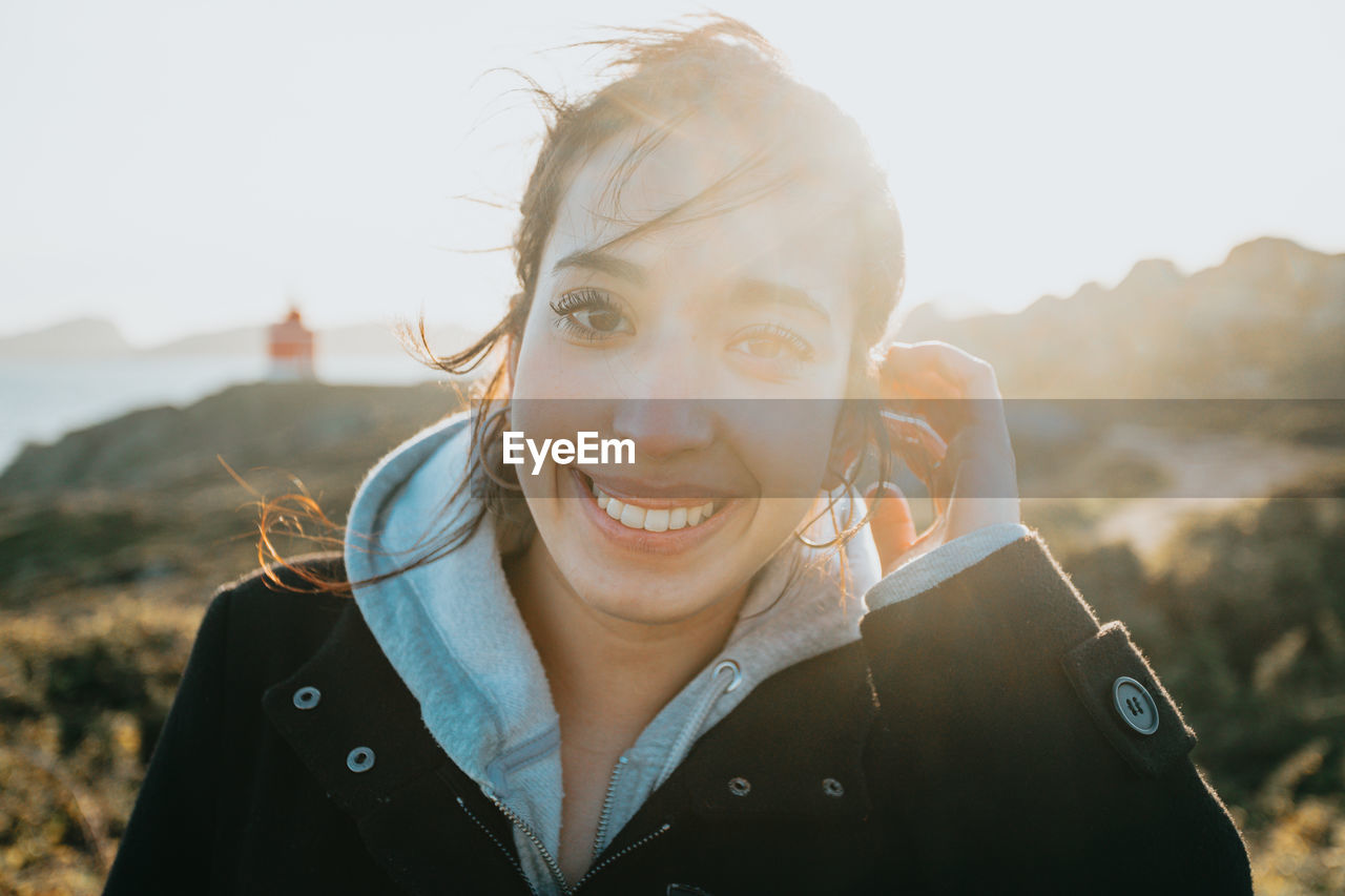 Portrait of young woman against sky