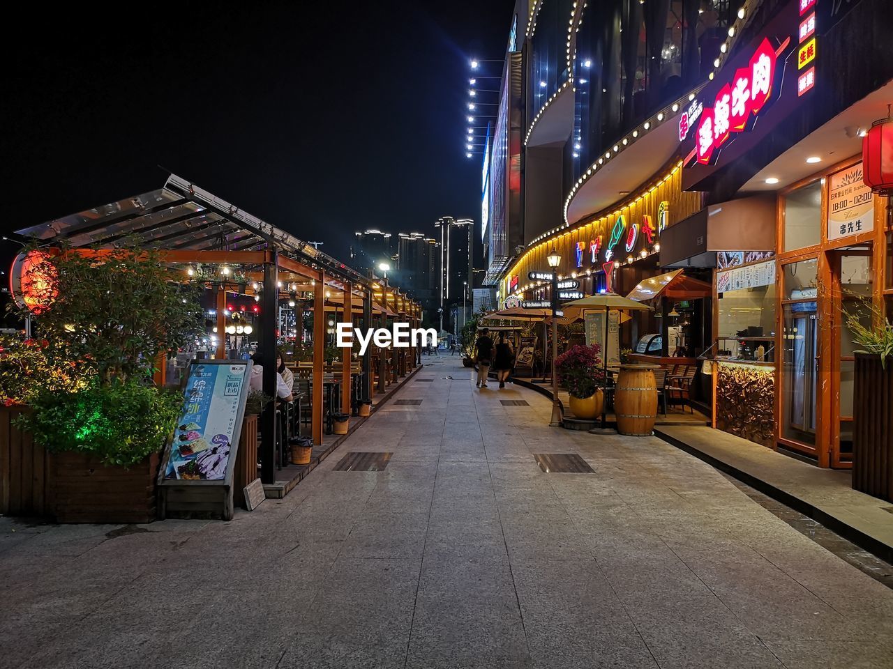 ILLUMINATED STREET AMIDST BUILDINGS AGAINST SKY AT NIGHT