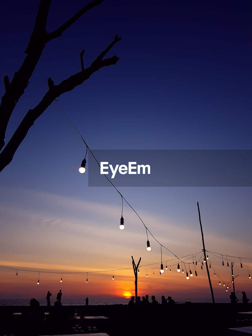 Low angle view of silhouette people hanging against sky at sunset