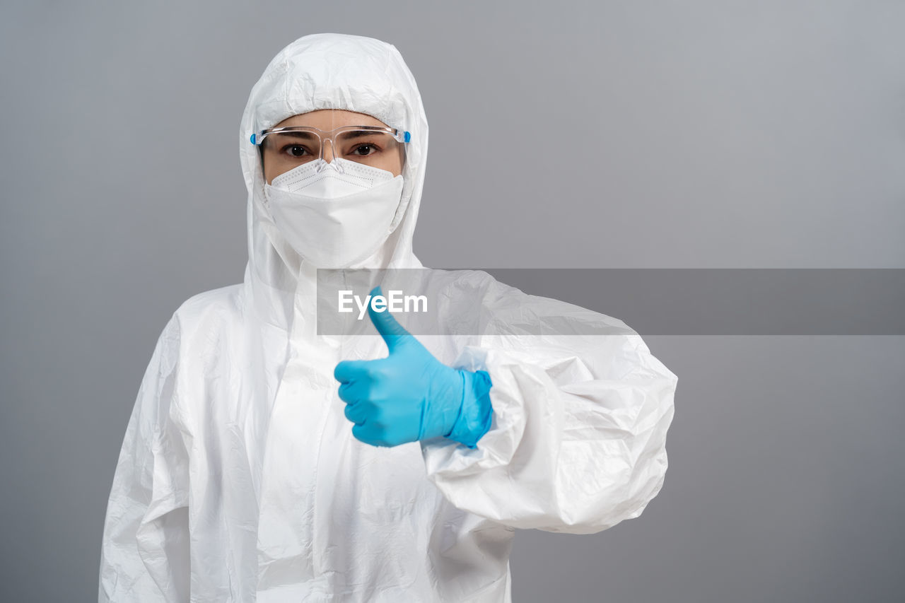protection, occupation, protective workwear, healthcare and medicine, science, scientist, protective mask - workwear, adult, indoors, security, surgical mask, research, professional occupation, one person, hygiene, laboratory, studio shot, scientific experiment, protective glove, portrait, expertise, person, technician, biochemistry, chemistry, clothing, doctor, working, occupational safety and health, protective eyewear, white, education, surgical glove, protective suit, biology, chemical, standing, lab coat, waist up, front view, holding, rubber, obscured face, poisonous, surgeon, looking at camera, cut out, biotechnology, copy space, skill, human face, mask