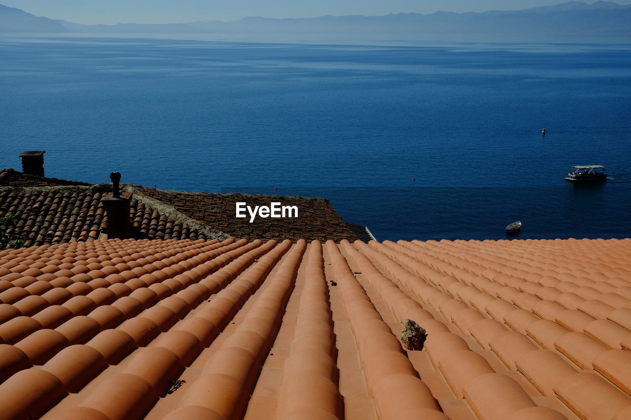High angle view of roof by sea against sky