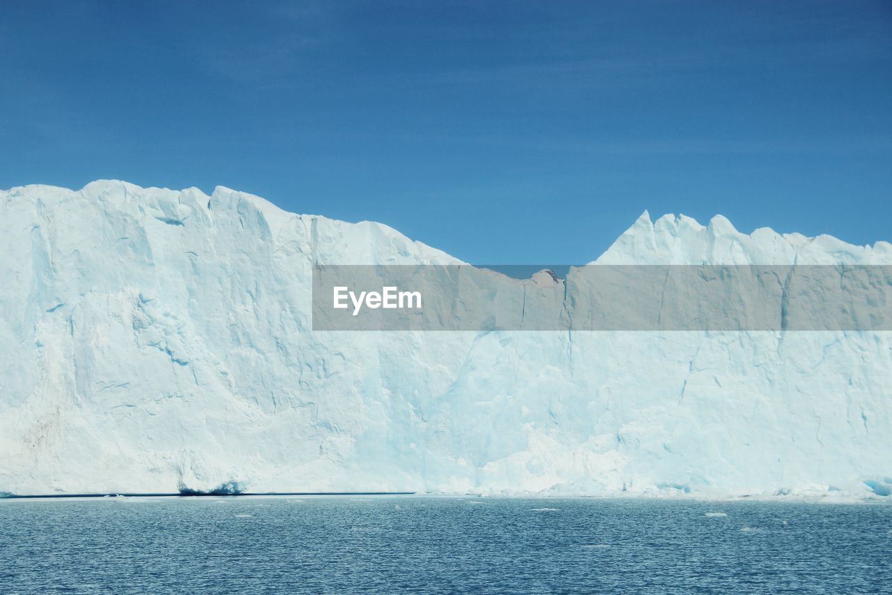 Scenic view of lake and glacier against clear blue sky