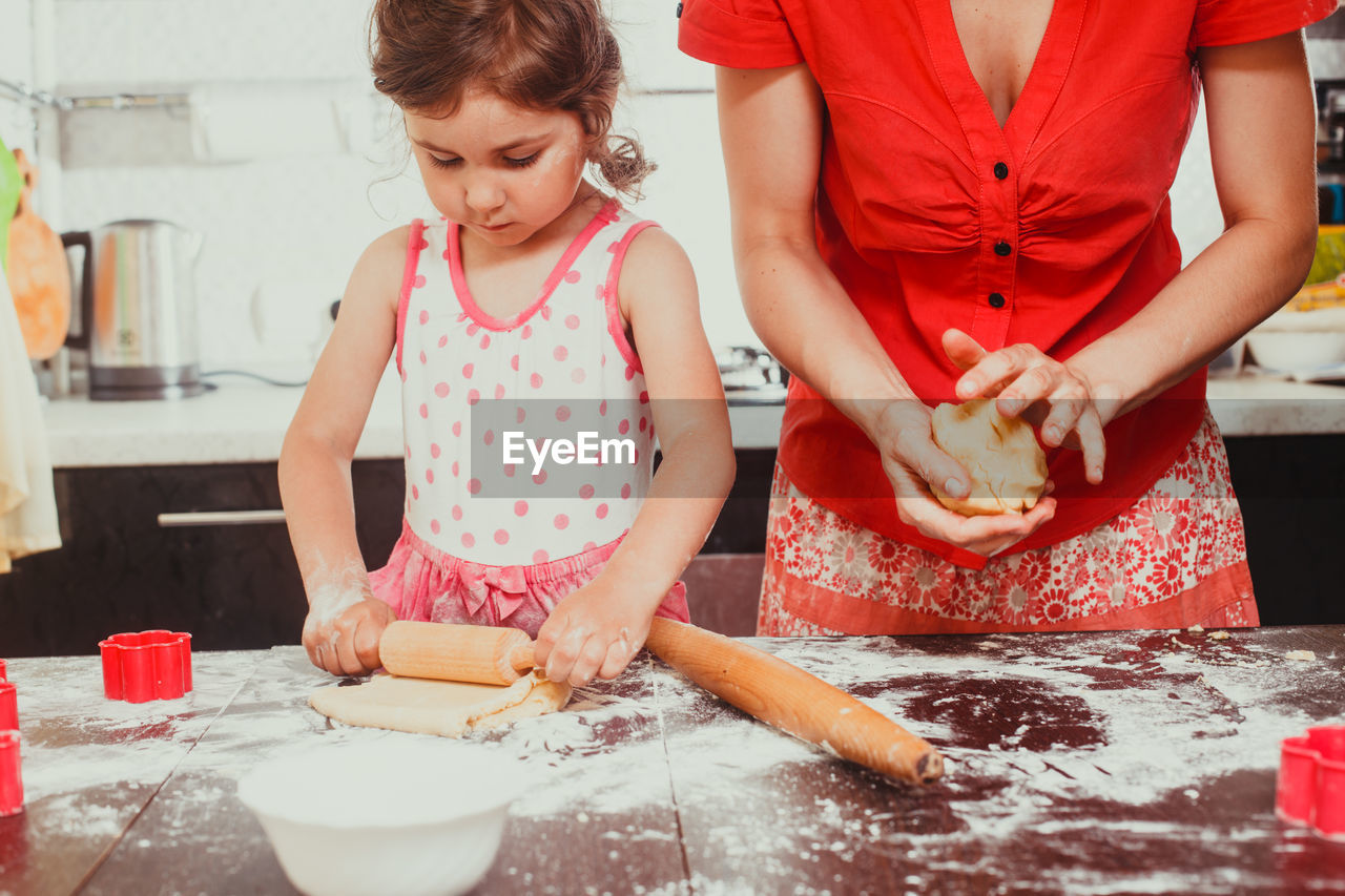 Cute girls preparing batter of cookies at home