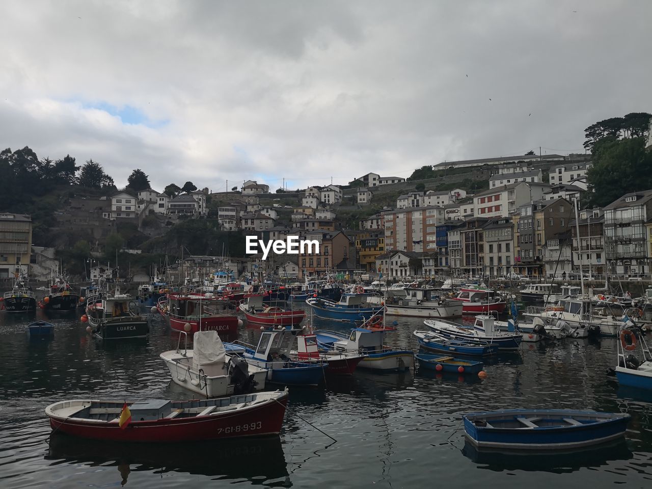 Boats moored on river by buildings in city against sky