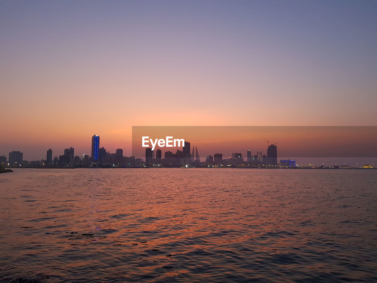 Sea and buildings against clear sky during sunset