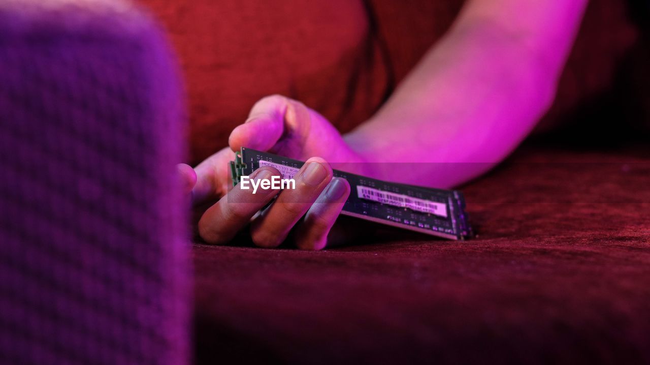 Cropped image of person holding computer chip on sofa