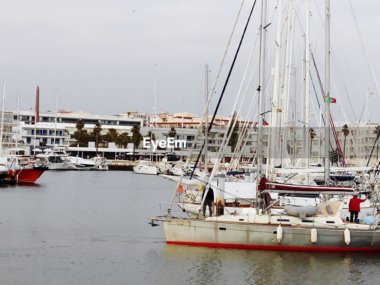 BOATS MOORED AT HARBOR AGAINST SKY