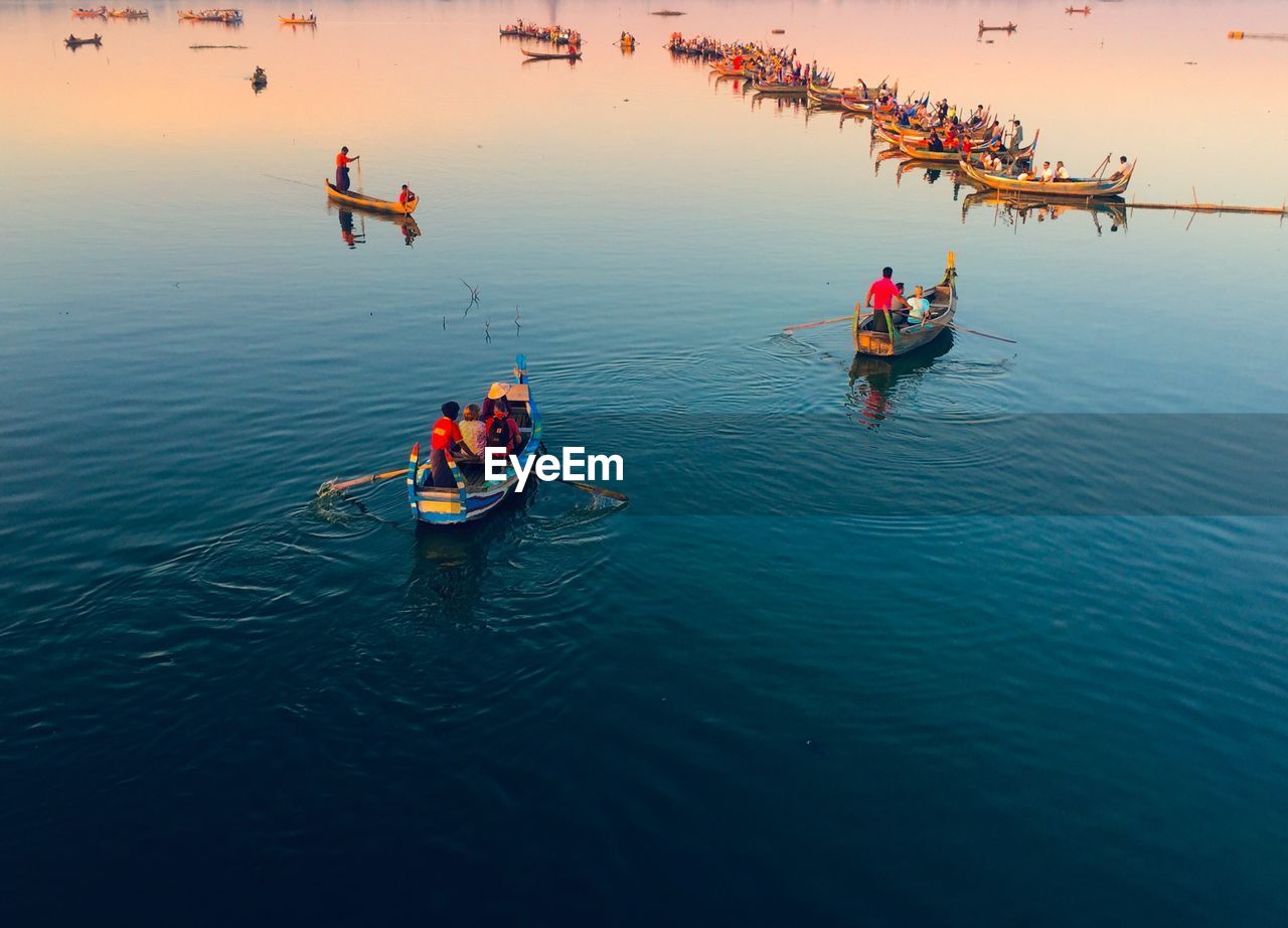 High angle view of people in boats on sea at sunset