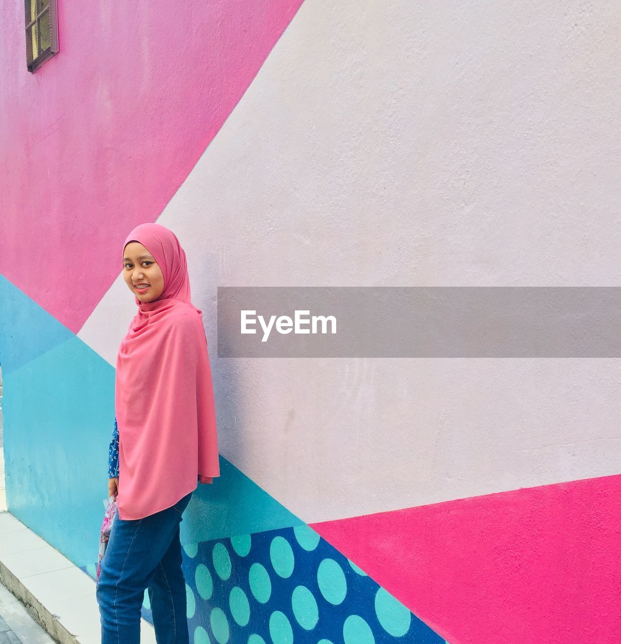 Portrait of smiling woman standing against colorful wall 