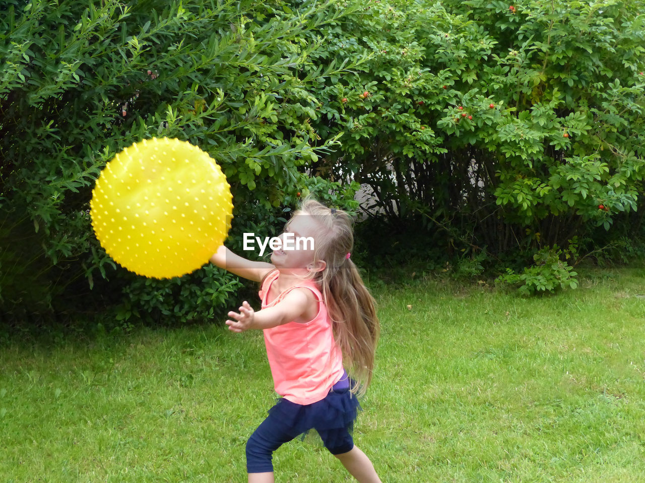 Cute girl playing with ball on grassy field at park