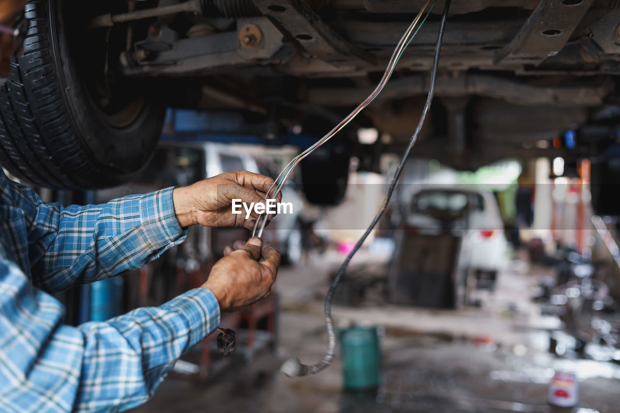 Midsection of mechanic working at workshop